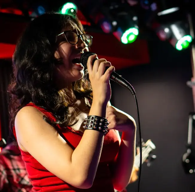 Alumna en clases de canto frente al micrófono en el escenario