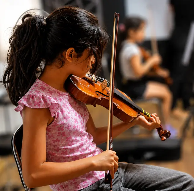 Niña en clases de violín grupales en la academia
